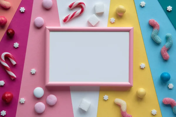 层彩纸上的空白粉红白色框架 将糖果 巧克力和糖果棒在空框架周围分类 复制空间 文字的位置 平躺在地上 尽收眼底 多姿多彩的问候设计 — 图库照片