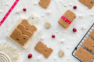 Spekuloos veya Spekulatius, Noel bisküvileri, çikolata topları ve beyaz tekstil masa örtüsünün üzerindeki kurdele. Geleneksel Alman tatlıları, Noel için kurabiyeler, Advent, kış atıştırmalıkları. Düz yatış, üst görünüm.