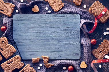 Spekuloos ya da Spekulatius, koyu dokulu arka planda Noel bisküvileri. Geleneksel Alman tatlıları, Noel için kurabiyeler. Kesme tahtası etrafında şenlikli bir çerçeve. Kopyalama alanı, metin için yer.