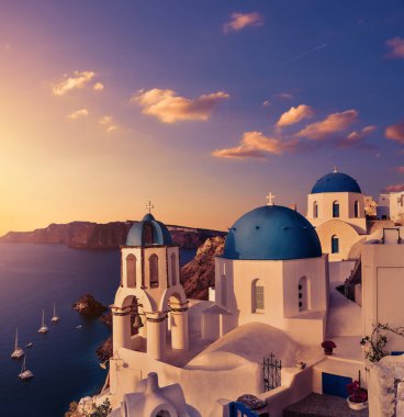 Santorini 'de Oia' da gün batımı. Yunanistan 'ın Santorini adasındaki Oia köyünde mavi kubbeli yerel bir kilise. Ton şeklinde, pembe ve mor. Güzel Yunan ada manzarası. Panoramik resim, kare bileşimi.