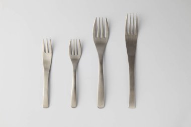 Beyaz arka planda paslanmaz çelik çatallar var.