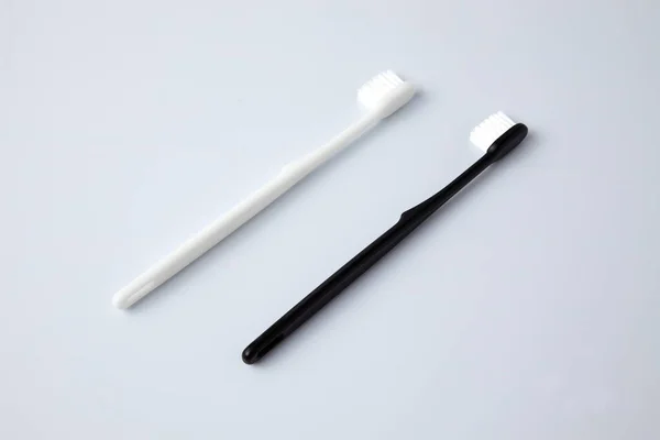 Cepillos de dientes negros blancos artículos de tocador aislados sobre fondo blanco — Foto de Stock
