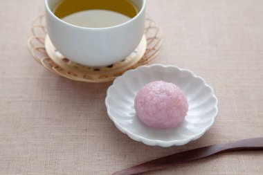Sakura mochi pirinç keki ve masa örtüsü üzerinde sıcak çay.