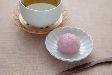Sakura mochi pirinç keki ve masa örtüsü üzerinde sıcak çay.