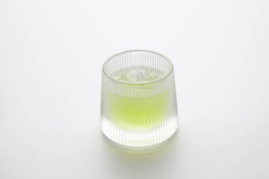 Bir bardak soğuk yeşil çay yakın plan beyaz arka planda izole edilmiş.