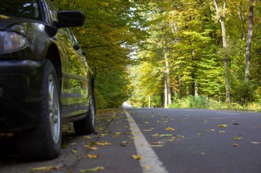 Orman yolunun yakınındaki yol kenarında bir araba. Bulanık arkaplan.
