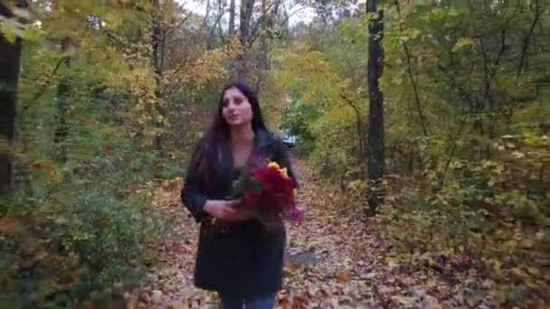 Mädchen mit Blumen spaziert im herbstlichen Wald — Stockvideo