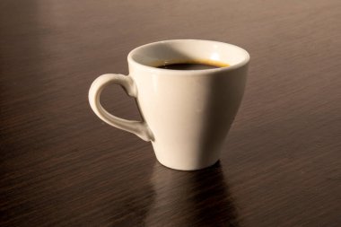 Masanın üzerinde beyaz bir fincan espresso.