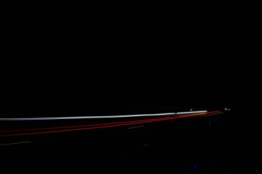 Yoldan geçen arabaların kırmızı ve beyaz ışıkları. Gece yolu.