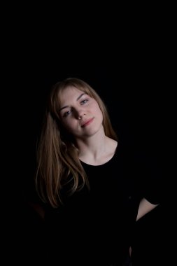 Siyah arka planda genç, tatlı, sarışın bir kız.
