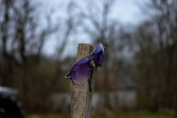 Sonnenbrille auf einer Holzstange. Unklarer Hintergrund. — Stockfoto