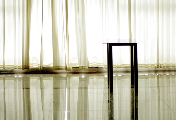 Sidan bordet framför vita upplysta gardin — Stockfoto