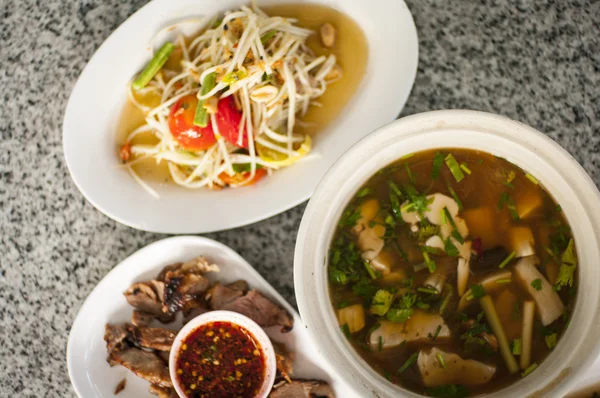 Tailandês picante conjunto de alimentos, sopa de cogumelos, salada de mamão e carne de porco bbq — Fotografia de Stock