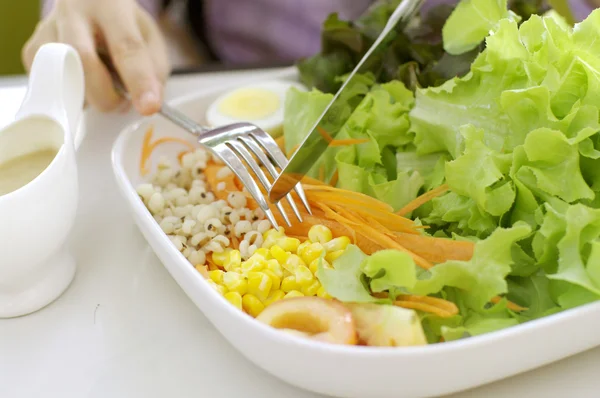 Chica comiendo ensalada con cuchillo y tenedor —  Fotos de Stock