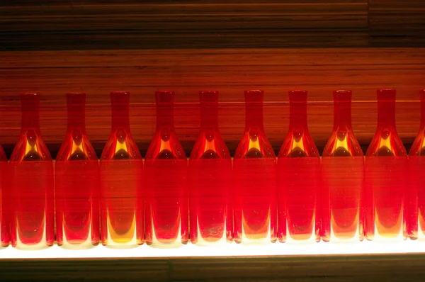 Fond abstrait de bouteilles en verre illuminé de lumière rouge — Photo