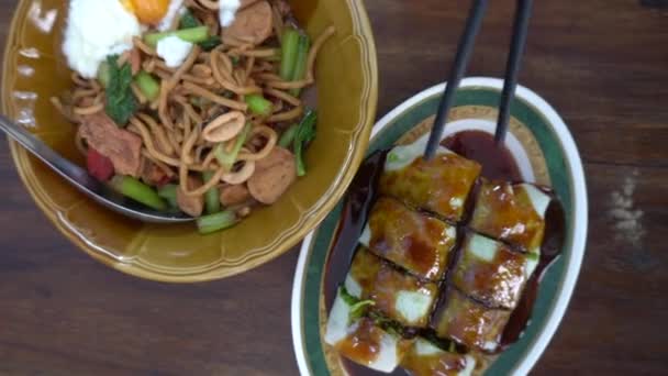 箸と手をシェアするトップビューの動きプーケットの地元の食べ物を共有する炒めホッキン麺とシーフードロール — ストック動画