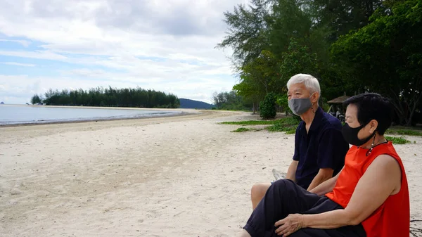Азиатская Старшая Пара Маске Расслабиться Сидя Пляже Бревно Белого Песка — стоковое фото