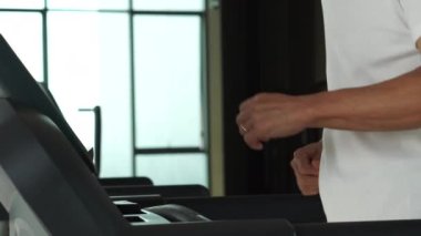 Asyalı son sınıf öğrencisi koşu bandında yürüyor egzersiz yapıyor ve spor yapıyor.