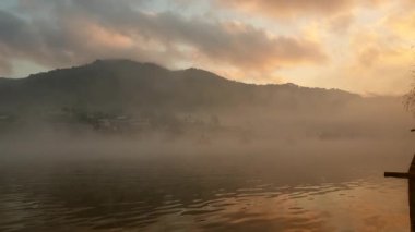 Mae Hong Son, Thailand city of mist. Beautiful sunrise and moving fog over lake with boats crusing slow motion