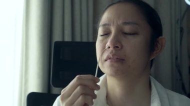 Asyalı kadın iş başında. Antijen test kiti yapıyor. Corona virüsü için genizden örnek alıyor.