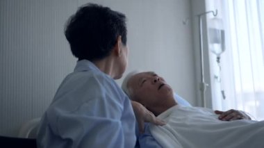 Asyalı kıdemli doktor hasta yatağında yatıyor. Karısı üzgün ve endişeli. Kendine iyi bak koca hastalığı.