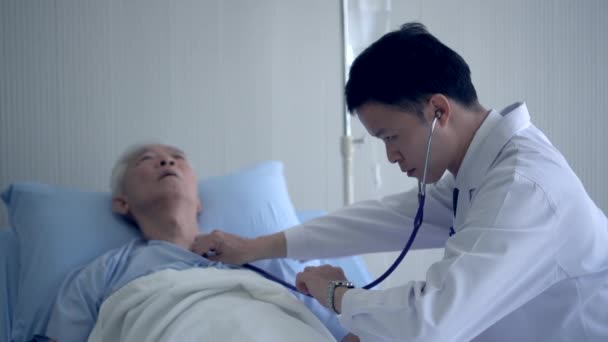 アジアの医師チェック心臓とパルス上のシニアで病院ベッドとともに聴診器 — ストック動画