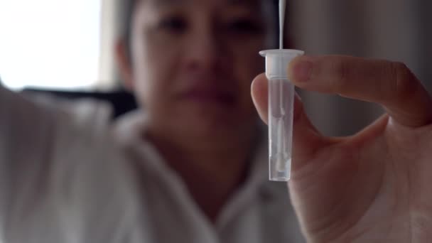 亚洲妇女做Covid Atk抗原鼻腔自我检测试剂盒 将鼻腔中的液体与管子中的抗氧化剂混合 — 图库视频影像