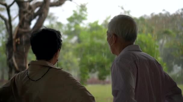 Asian Elderly Couple Waiting Rain Stop Unexpected Strom While Walking — Stock Video