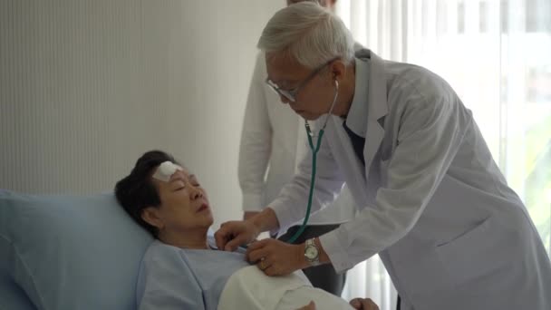 Starszy Lekarz Sprawdzić Tętno Pacjenta Podeszłym Wieku Rodziną Stetoskopów Czeka — Wideo stockowe