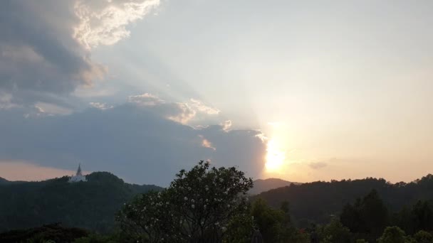 風景の中にタイの白い塔の寺院で熱帯の山の上に雲の後ろの夕日 — ストック動画