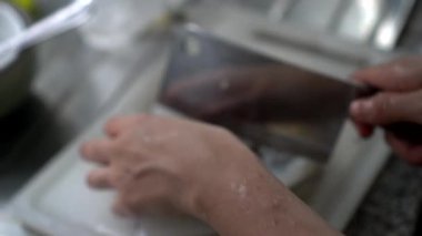 Mutfakta çiğ mürekkep balığı hazırlıyorum. Deniz ürünlerini bıçak kabuğu soyarak yıkıyorum.