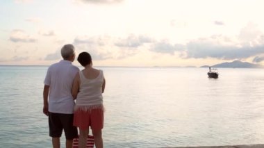 Asya 'lı son sınıf öğrencisi bir kadın, tropik okyanusta sabah teknesinden bahsederken eğleniyor.