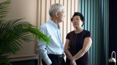 Zengin, zengin, Asyalı, yaşlı çift konuşuyor. Lüks ev içinde gülerek gülüyorlar.