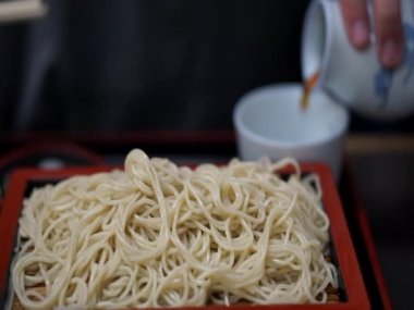 Asyalı adam taze Japon eriştesi yiyor. Dişhi soya soslu erişte çorbası ve pırasa.