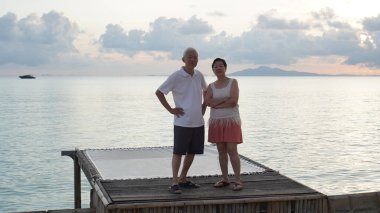 Asyalı yaşlı çift rahatlayın tropikal deniz kenarı tatil tatilinde iyi eğlenceler.