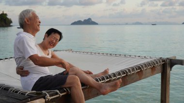 Asyalı yaşlı çift rahatlayın tropikal deniz kenarı tatil tatilinde iyi eğlenceler.