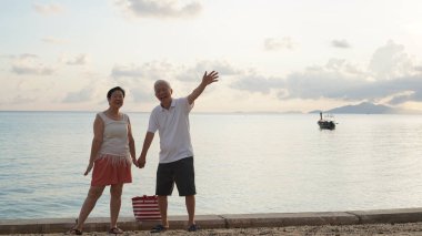 Asyalı yaşlı çift rahatlayın tropikal deniz kenarı tatil tatilinde iyi eğlenceler.