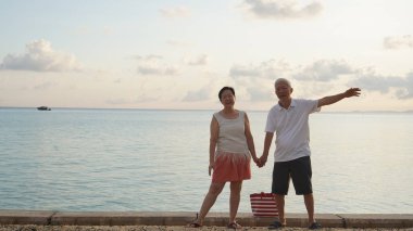 Asyalı yaşlı çift rahatlayın tropikal deniz kenarı tatil tatilinde iyi eğlenceler.