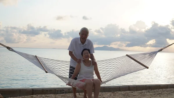 Asian senior elder couple relax enjoy have fun on tropical seaside morning vacation retirement trip together
