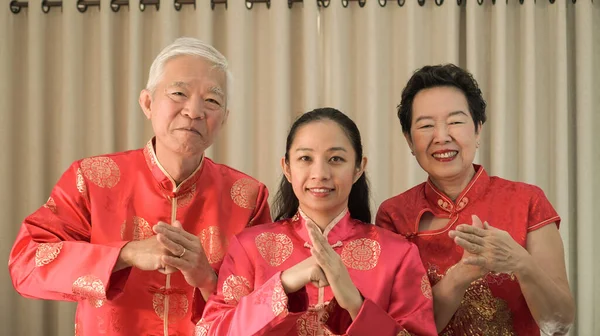 Asian family gathering Chinese New Year celebration in red traditional costume greeting red envelop