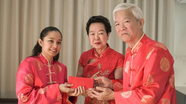 Asian family gathering Chinese New Year celebration in red traditional costume greeting red envelop