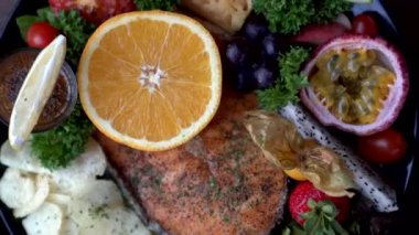 Rustic seafood steak salmon fillet grill serve with fruits orange passion fruit and salad top view