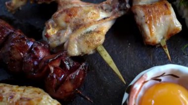 Çeşitli yakitori şişleri Japon usulü ızgara izakaya tavuk derisi ciğer ve çiğ yumurta sarısı soslu et.