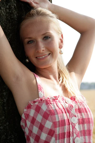 Young woman leaning agaisnt a tree — Stock Photo, Image