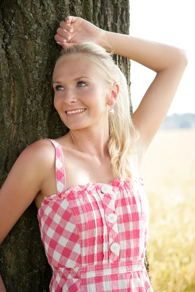 Young woman leaning agaisnt a tree — Stock Photo, Image