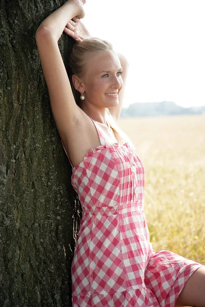 Giovane donna appoggiata contro un albero — Foto Stock