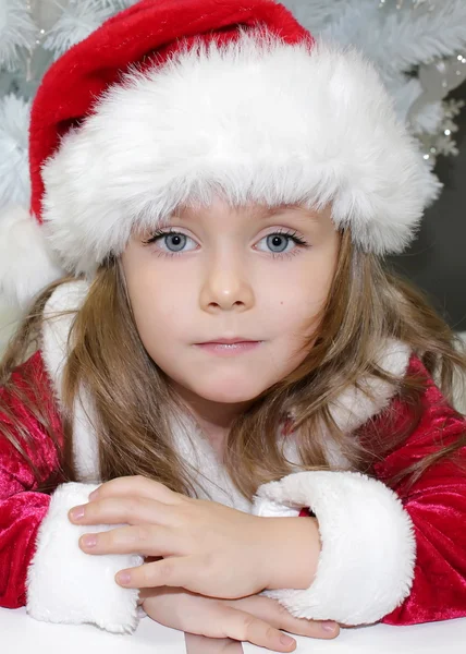 Κορίτσι με κόκκινο χρώμα, ντυμένος σαν τον Άγιο Βασίλη με το χριστουγεννιάτικο δέντρο — Φωτογραφία Αρχείου