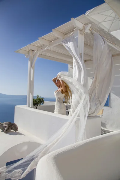 Hermosa novia en un vestido de novia en Santorini con un largo velo — Foto de Stock