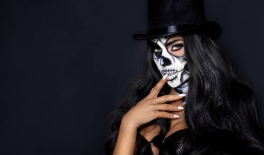 Cadılar Bayramı makyajında siyah arka planda güzel bir model. Silindir şapkalı ve kafatası makyajlı seksi kadın. Cadılar Bayramı makyaj konsepti.
