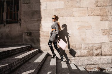 Yüksek model. Zarif kıyafetli ve şık çizmeli seksi kadın dışarıda poz veriyor. Şık giyimli manken. Zarafet. Bahar, yaz modası.